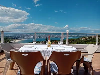 a table with wine glasses on a balcony with a view at Apartament Zaliva in Varna City