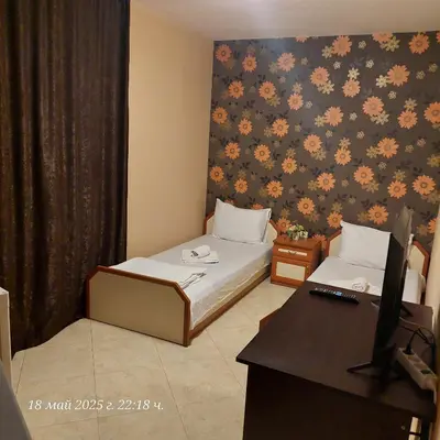 a room with two beds and a desk with a computer at Hristovi Apartments & Studios in Pomorie