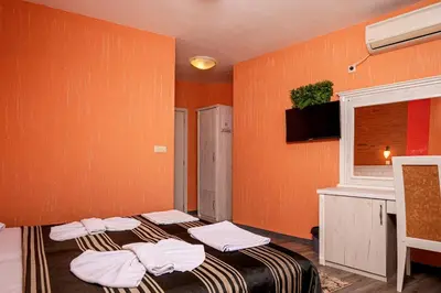 two beds in a room with orange walls at Family Hotel Paros in Pomorie