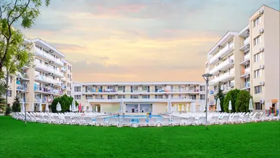 an exterior view of a hotel with chairs and a lawn at Hotel Garden Nevis - All Inclusive in Sunny Beach