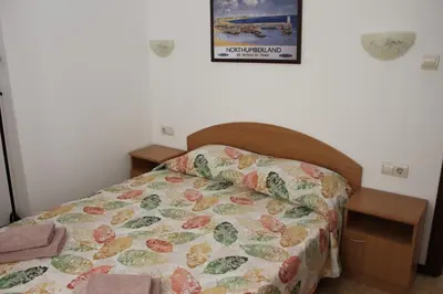 a bedroom with a bed with a floral bedspread at Hotel Radik in Sozopol