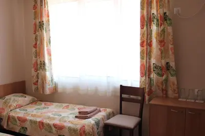 a bedroom with a bed and a chair and a window at Hotel Radik in Sozopol