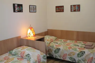 a bedroom with two beds and a table with a lamp at Hotel Radik in Sozopol