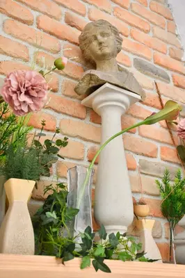 a statue of a woman on a pedestal in front of a brick wall at Family Hotel Apolonia in Sozopol