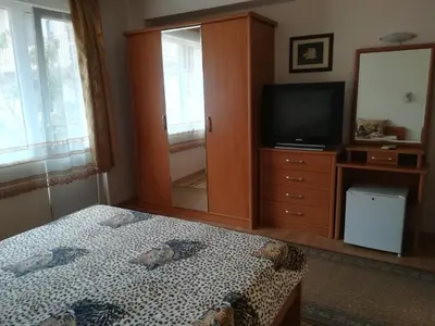 a bedroom with a bed and a dresser with a television at Guest House Georgieva Ravda in Ravda