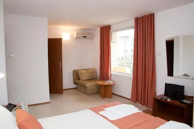 a hotel room with a bed and a chair and a window at Mappy Holidays Aparthotel in Sozopol