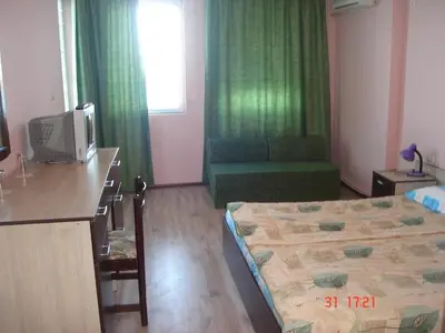 a room with a bed and a desk with a television at Guest House Rusalka in Sozopol