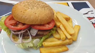a white plate with a hamburger and french fries at Hotel Villa Bora in Sunny Beach