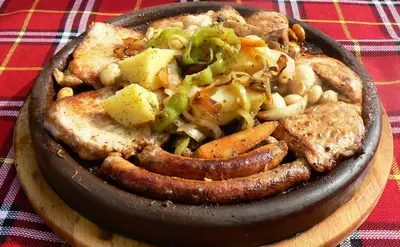 a bowl of food with sausage and vegetables on a table at Hotel Villa Bora in Sunny Beach