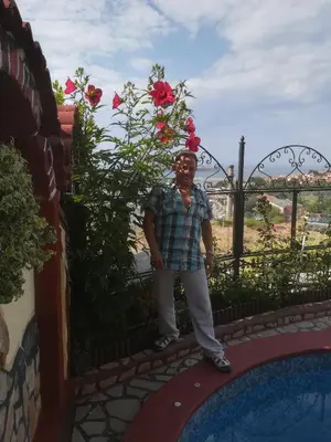 a man standing in front of a fence with flowers at Guest House Hetodon in Sozopol