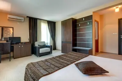 a hotel room with a large bed and a desk at Siena House in Sozopol
