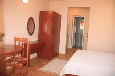 a bedroom with a bed and a table and a mirror at Family Hotel Emilia in Sozopol