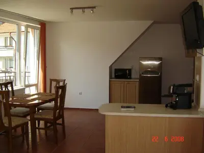 a kitchen and dining room with a table and a refrigerator at Panoramic Penthouse Sozopol in Sozopol