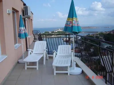 a balcony with two chairs and two umbrellas at Panoramic Penthouse Sozopol in Sozopol