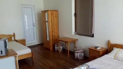 a bedroom with two beds and a table and a door at Guest House Diamant in Sozopol