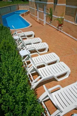 a row of white lounge chairs next to a pool at Hotel Luxor in Lozenets