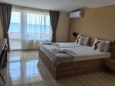 a bedroom with a large bed and a large window at Family Hotel Alfa Vita in Sozopol