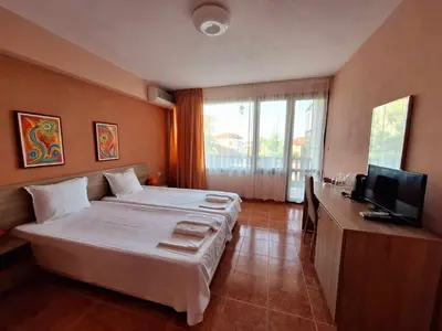 a hotel room with a large bed and a television at Guest House Starata Kushta in Lozenets