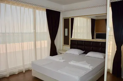 a bedroom with a white bed with a large window at Golden Rainbow Beach Hotel in Sunny Beach