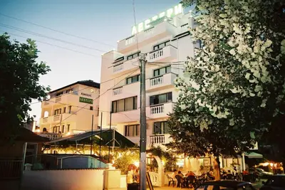 a tall white building with people in front of it at Hotel Levteri in Primorsko