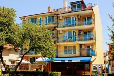 an apartment building with blue balconies and a tree at R&G Hotel in Nesebar