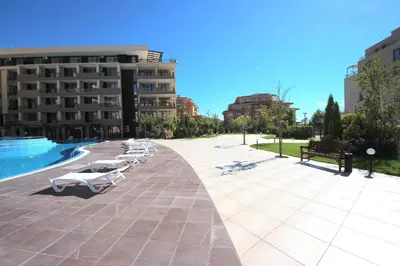 a row of lounge chairs on a sidewalk next to a building at Menada Luxor Apartments in Sveti Vlas