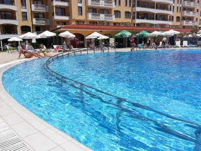 a large swimming pool in a hotel with people sitting at Menada Royal Sun Apartments in Sunny Beach