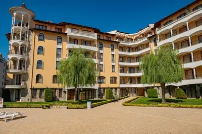 a large apartment building with trees in front of it at Menada Royal Sun Apartments in Sunny Beach
