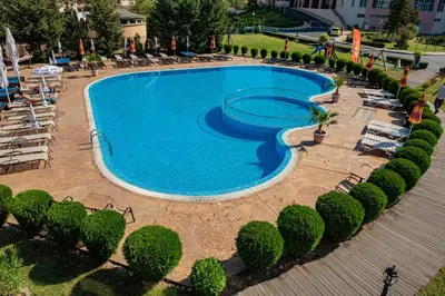 a large swimming pool with lounge chairs and trees at Menada Sunny Beach Plaza Apartments in Sunny Beach