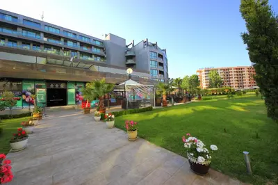 a park with potted plants in front of a building at Menada Sunny Beach Plaza Apartments in Sunny Beach