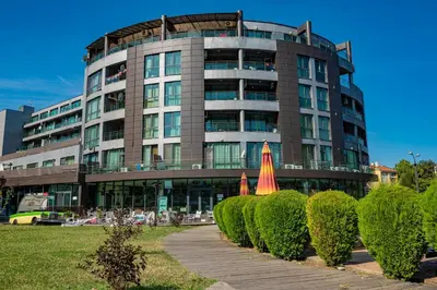a large building with a bunch of bushes in front of it at Menada Sunny Beach Plaza Apartments in Sunny Beach