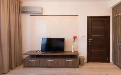 a living room with a television on a wooden entertainment center at City Apartments Triumph in Varna City