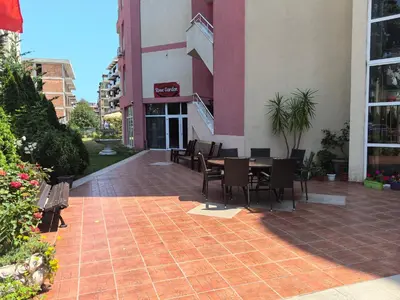 a patio with a table and chairs in front of a building at Rose Garden Omax Apartments in Sunny Beach