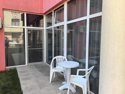 a patio with two chairs and a table in front of a building at Rose Garden Omax Apartments in Sunny Beach