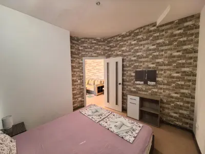 a bedroom with a bed and a brick wall at Rose Garden Omax Apartments in Sunny Beach