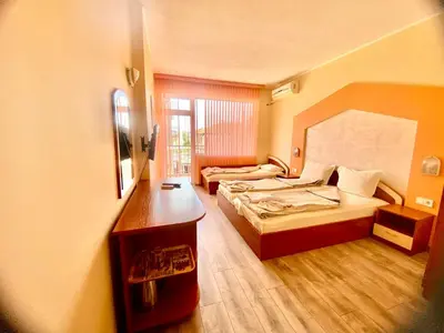 a hotel room with two beds and a desk at Guest house Napoli in Ravda