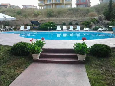 a swimming pool with some plants and some chairs at Villa Rouge in Sozopol