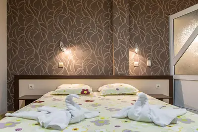 a bedroom with two swans sitting on a bed at Семеен хотел Адена in Chernomorets