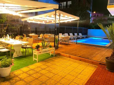 a patio with a table and a swimming pool at night at Family Hotel Saga in Ravda