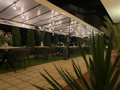 a patio with tables and chairs and lights at Family Hotel Saga in Ravda
