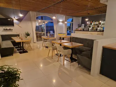 a restaurant with tables and couches and a bar at Family Hotel Saga in Ravda