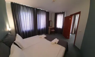 a bedroom with a white bed with two towels on it at Family Hotel Saga in Ravda