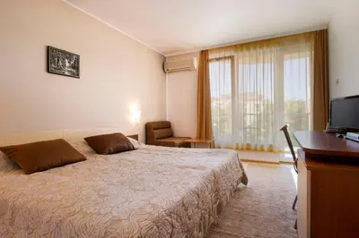 a bedroom with a bed and a desk and a television at Hotel Tropics & Venera - Ultra All Inclusive in Sveti Vlas