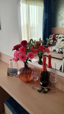a table with a vase of flowers and two wine glasses at Blue Bay Hotel in Sunny Beach