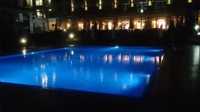a large blue swimming pool at night with a building at Nedev's Apartments in Kavatsi Area in Sozopol