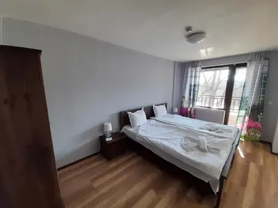a bedroom with a bed with white sheets and a window at Complex Strandzhata in Burgas City