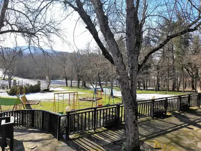 a fence around a park with a tree and a playground at Complex Strandzhata in Burgas City
