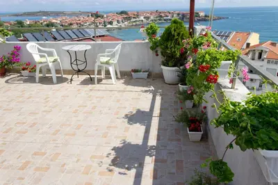 a patio with chairs and flowers on a balcony at House Prodanovi in Sozopol
