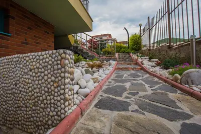a walkway with rocks and a fence next to a building at JBH Hotel in Sveti Vlas