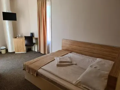 a bedroom with a bed with a wooden headboard and a desk at Hotel Mida in Obzor